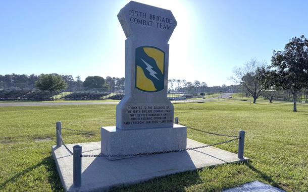 A monument on a grassy field against a blue sky.