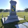 A monument on a grassy field against a blue sky.
