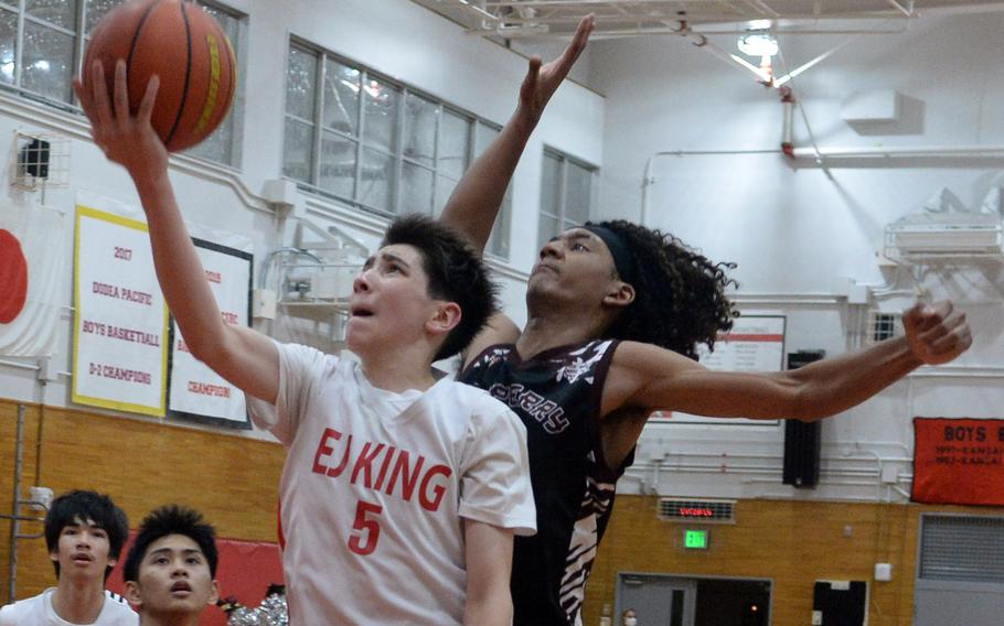 E.J. King's Cameron Reinhart drives for a layup past Matthew C. Perry's Shion Fleming during Friday's DODEA-Japan boys basketball game. The Cobras won 57-53.