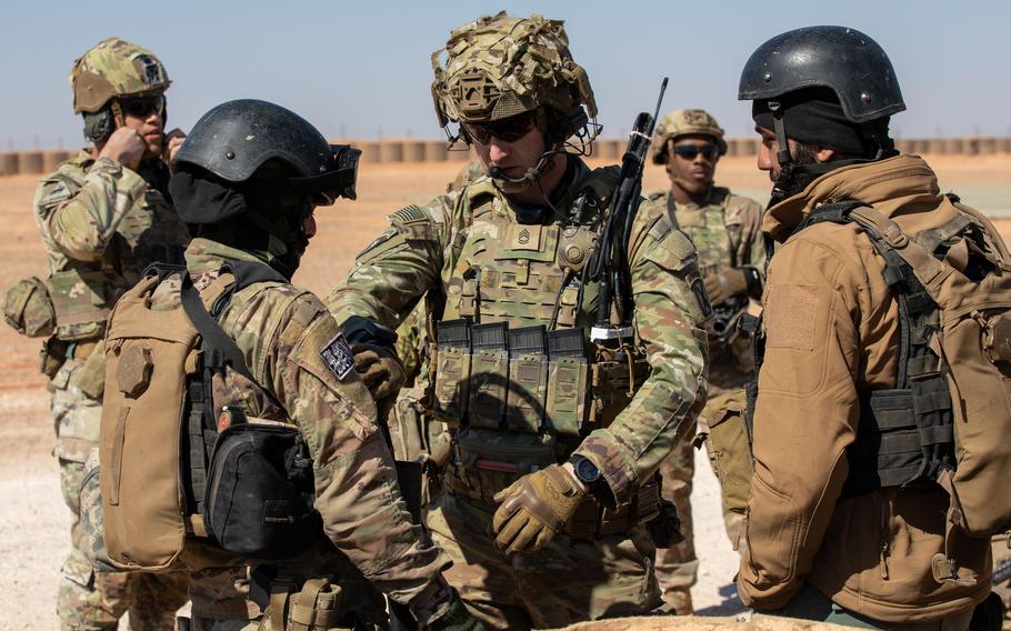 A U.S. soldier checks the gear of Syrian partner forces.