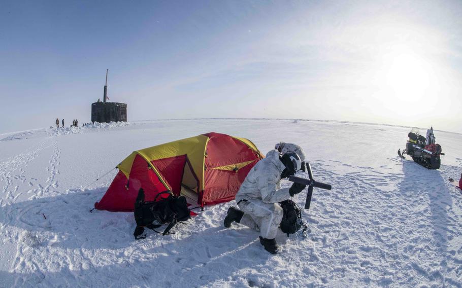 A Navy SEAL uses a radio on the ice next to the attack submarine USS Hampton during an integration exercise with Norwegian naval special operations commandos Saturday, March 9, 2024, as part of Arctic Edge.