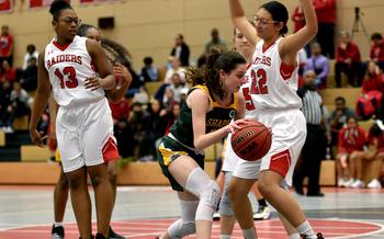 SHAPE's Jessica Moon drives to the basket as Kaiserslautern's Emma Arambula defends Friday evening at Kaiserslautern High School in Kaiserslautern, Germany. Following at left is the Raiders' Cambrielle Sanders.