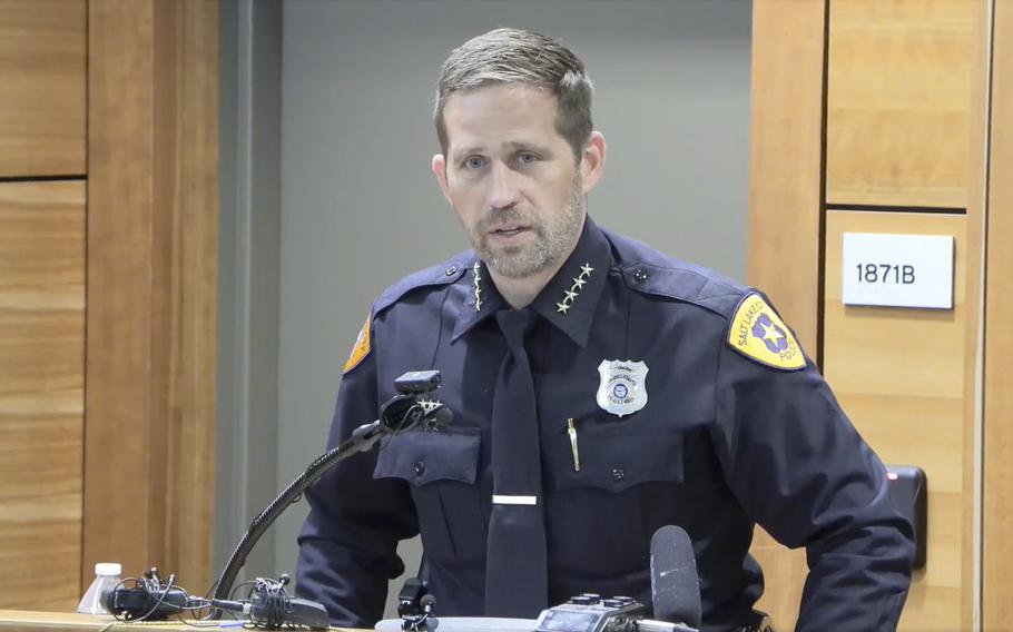 A police man leans forward slightly while speaking at a podium.