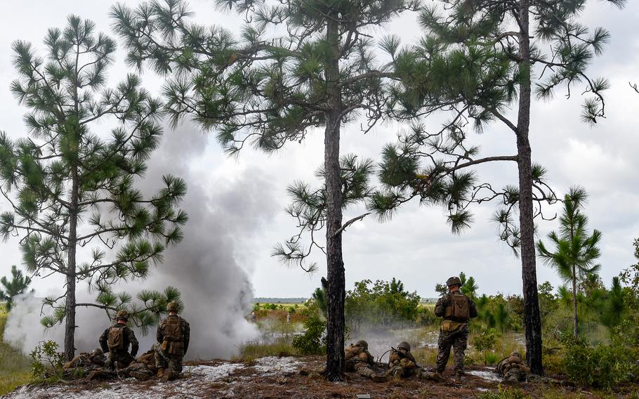 A claymore mine blast sends smoke in the air as Marine infantry students open fire from a tree line on Camp Lejeune, N.C., training grounds on Aug. 27, 2021. The students were practicing an ambush during an initial infantry training pilot program meant to drastically change the way the Corps trains its infantrymen. The pilot program expands infantry training from nine to 14 weeks and places Marines in 14-person squads under a single instructor.