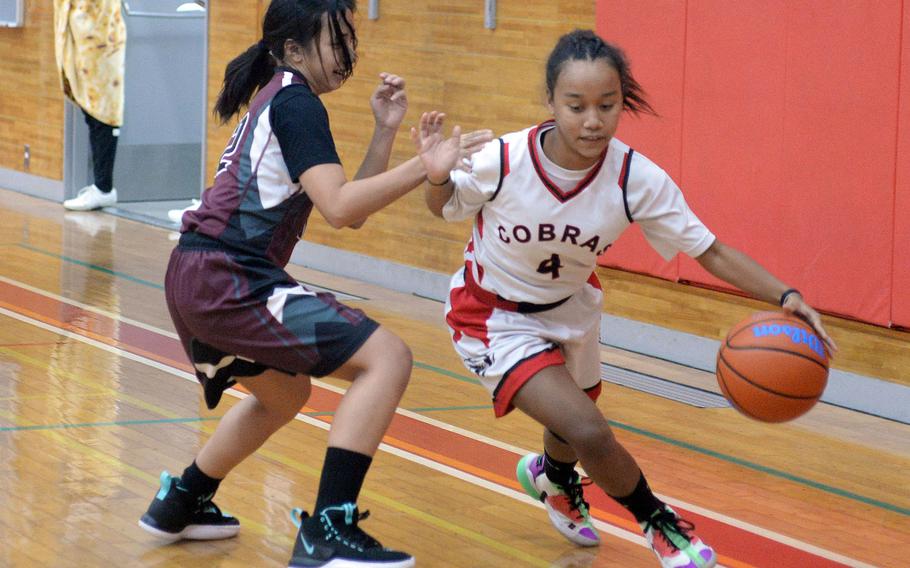 E.J. King's Miu Best dribbles past Matthew C. Perry's Aiya Versoza during Friday's DODEA-Japan basketball game. The Cobras won 55-4.