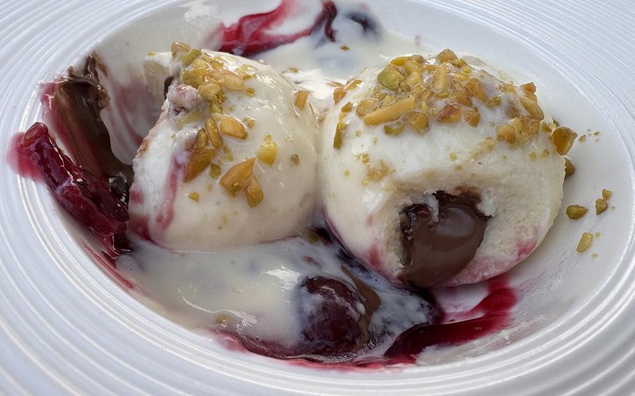 A nougat dumpling, served on a bed of cherry compote and topped with vanilla sauce hides a creamy Nutella center.