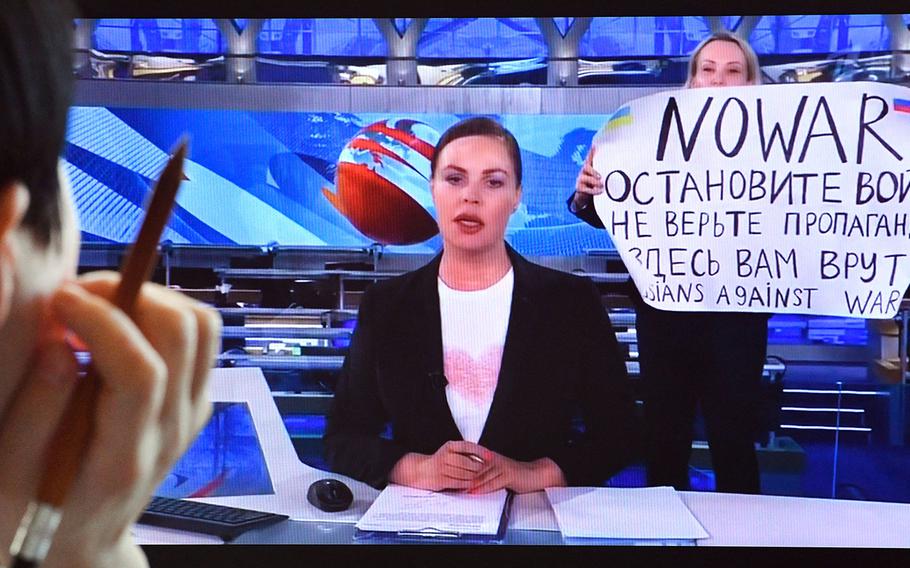 A woman looks at a computer screen watching a dissenting Russian Channel One employee entering Ostankino on-air TV studio during Russia’s most-watched evening news broadcast, holding up a poster which reads as “No War” and condemning Moscow’s military action in Ukraine in Moscow on March 15, 2022. - As a news anchor Yekaterina Andreyeva launched into an item about relations with Belarus, Marina Ovsyannikova, who wore a dark formal suit, burst into view, holding up a hand-written poster saying “No War” in English.