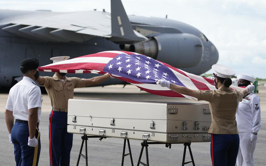 U.S. military drape a national flag over the possible remains of a WWII U.S. airman found in northern Thailand, during a repatriation ceremony Wednesday, May 18, 2022, at the U-Tapao Air Base in Rayong province, eastern Thailand. 