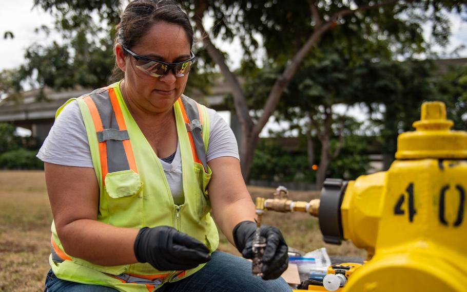 A Navy contractor collects a water sample on April 8, 2022, at Catlin Park, a military housing community near Joint Base Pearl Harbor-Hickam, as part of a long-term water monitoring plan.