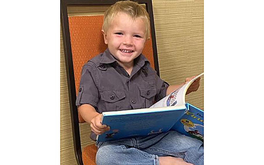 A video screen grab shows one of the 12 escaped hostages, a 3-year-old boy, smiling as he looks at a book on Dec. 18, 2021, after returning to the states.