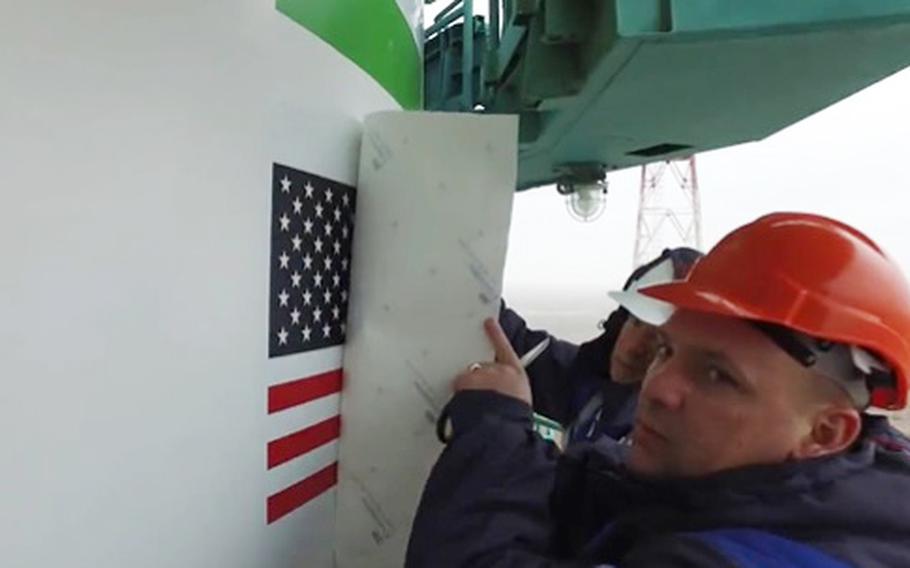 Workers cover an American flag on a rocket at Baikonur Cosmodrome, a Russian spaceport in southern Kazakhstan, in this screenshot from a video posted to Twitter on March 3, 2022. 