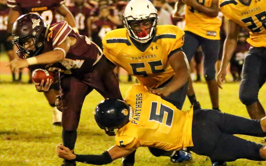 Father Duenas' Jaron Meno tries to evade Guam High defenders Laethain Gumabon and Cedric Murphy.