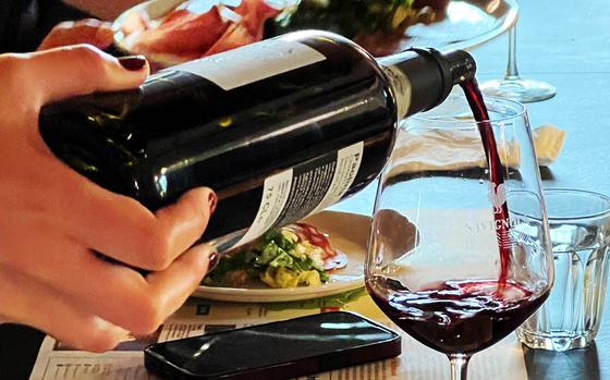 A hand pours red wine into a wine glass.