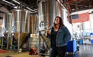 A woman holds a glass of beer in a brewery.