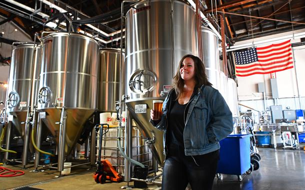A woman holds a glass of beer in a brewery.