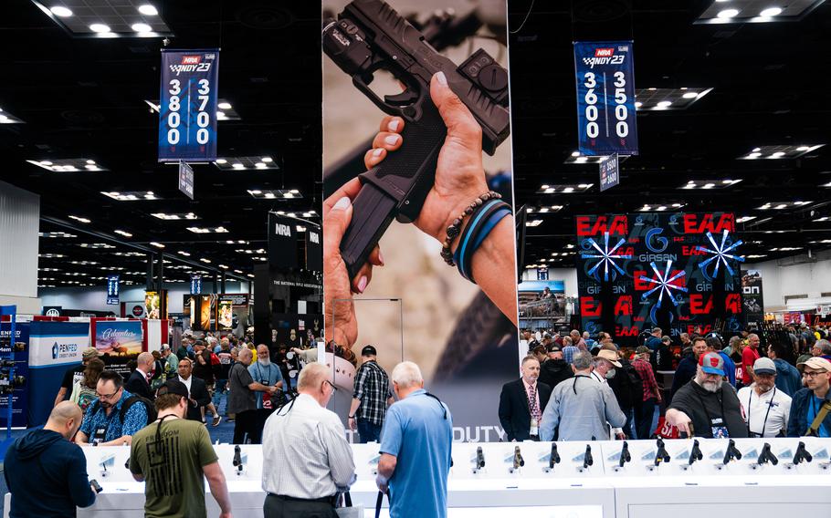 Attendees look at guns during the National Rifle Association annual convention at the Indiana Convention Center in Indianapolis on April 14, 2023. 