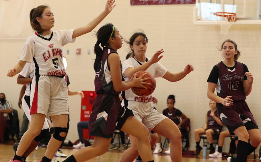 Matthew C. Perry's Aiya Versoza drives to the basket between E.J. King's Aileen FitzGerald and Maliwan Schinker during Saturday's DODEA-Japan basketball game. The Cobras won 49-13.