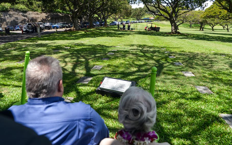 Family members of Navy Cmdr. Frederick Schrader watch as his casket is lowered into the ground at the National Memorial Cemetery of the Pacific in Honolulu, Hawaii, April 13, 2023.