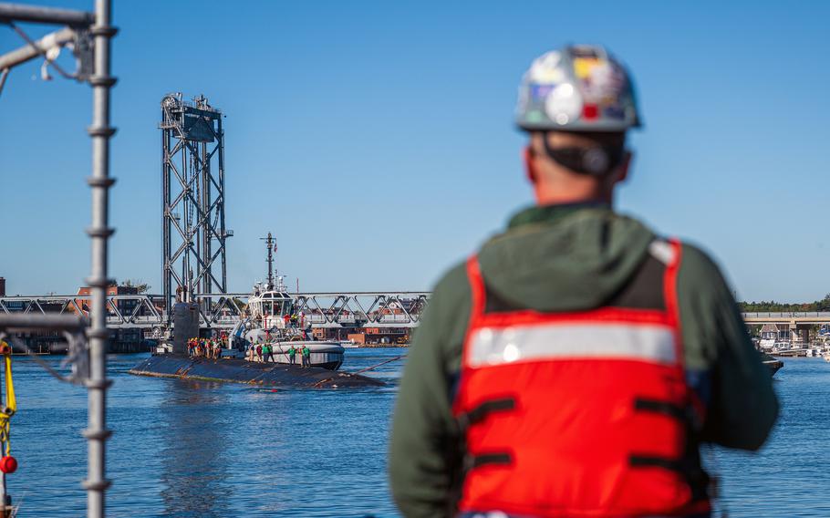 Worker watches submarine enter shipyard.