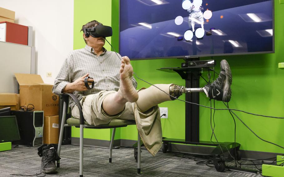 Navy veteran Frederick Dean Peterson, wearing a VR headset, lifts his legs as he demonstrate a new therapy called Mr. MAPP (Mixed reality system for Managing Phantom Pain) at University of Texas at Dallas in Richardson on Monday, Nov. 28, 2022. Peterson took part in the clinical trial of the therapy that helps the user by creating a virtual image of their missing limb. (Shafkat Anowar, The Dallas Morning News/TNS)