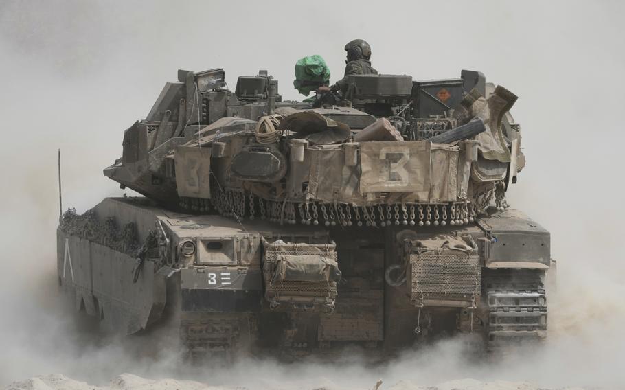 An Israeli tank kicks up dust as it moves.
