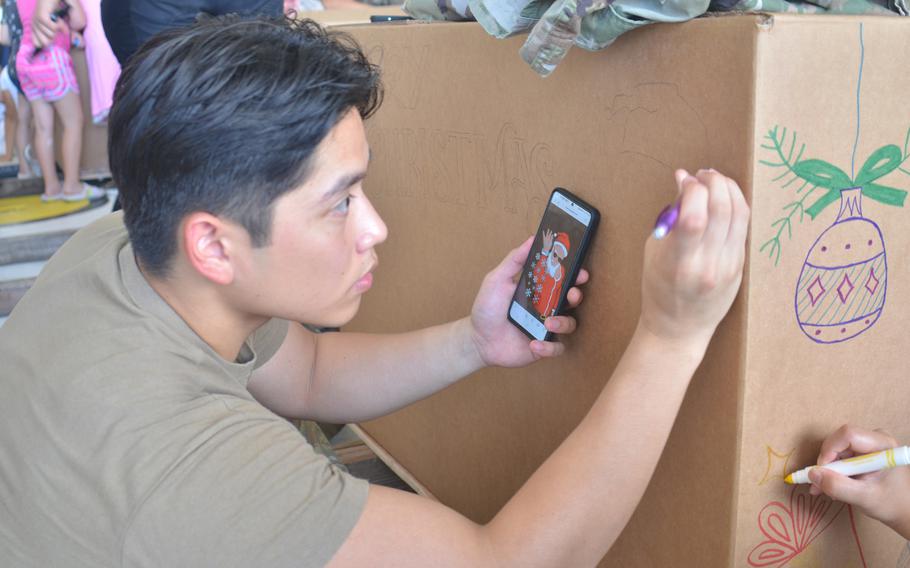 Air Force Staff Sgt. Diyco Lawrence decorates an Operation Christmas Drop bundle at Andersen Air Force Base, Guam, Saturday, Dec. 2, 2023.