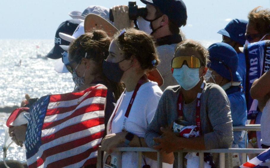 Lt. j.g. Nikki Barnes, in dark mask, the first U.S. Coast Guardsman to represent the United States at the Olympics, watches the men’s 470 race from Enoshima, Japan, Wednesday, Aug. 4, 2021. 