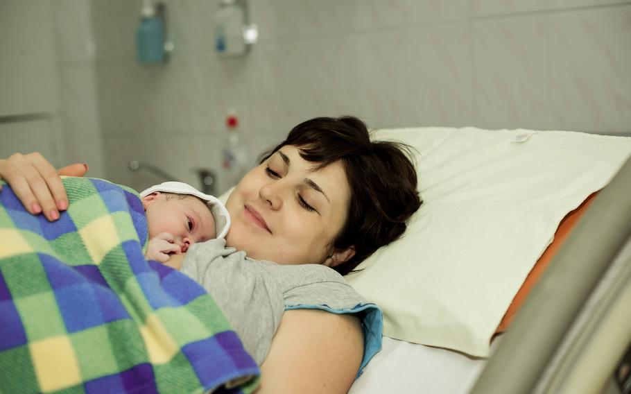 Happy woman after the birth of a newborn baby on a bed