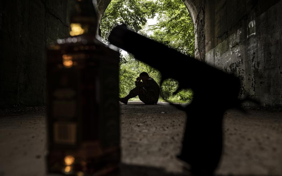 A service member sitting in a shadow of a tunnel with a handgun in the foreground.