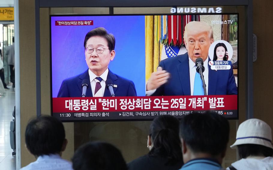 People watch a TV screen at a train station showing side by side file images of the South Korean president and the U.S. president.