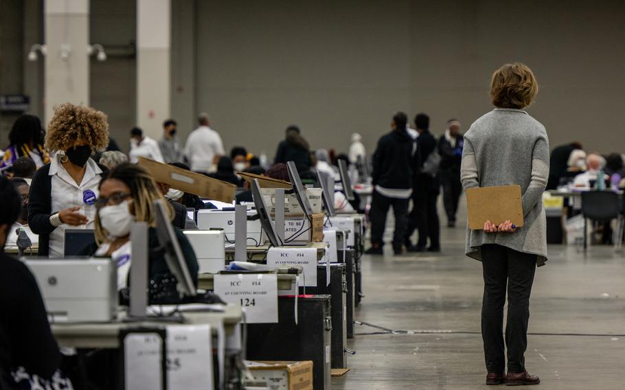 In this photo from Nov. 8, 2022, a poll challenger oversees election inspectors at the Huntington Place convention center in Detroit. 