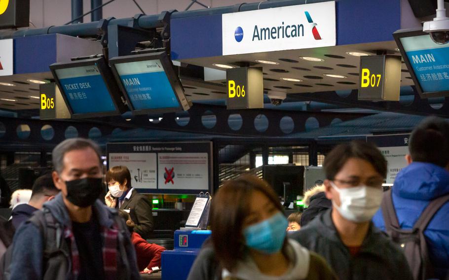 Travelers wearing face masks line up to check in for an American Airlines flight to Los Angeles at Beijing Capital International Airport in Beijing, Thursday, Jan. 30, 2020.