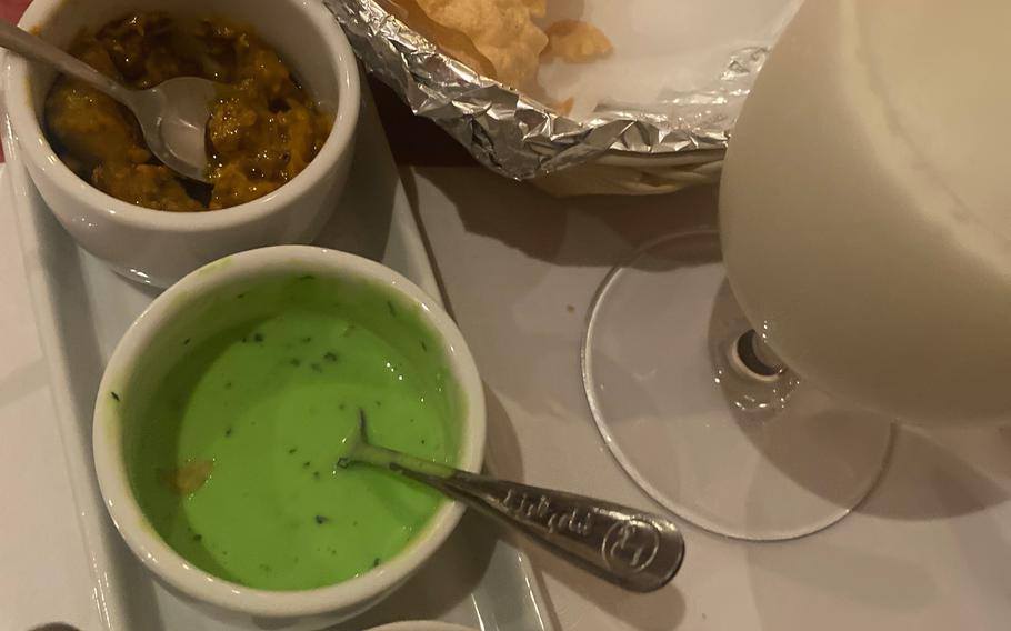 Papad, a crispy, gluten-free Indian bread made from lentils, is accompanied by a three-sauce assortment at Curry House in Kaiserslautern, Germany. Also pictured is a sweet lassi.
