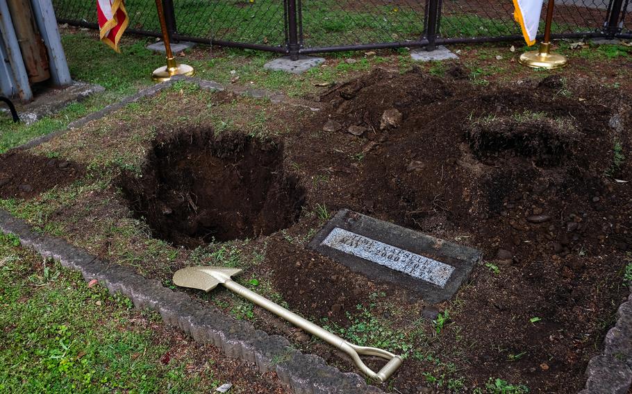 A shovel sits on the ground next to a hole where a time capsule was buried at an elementary school on Yokota Air Base.