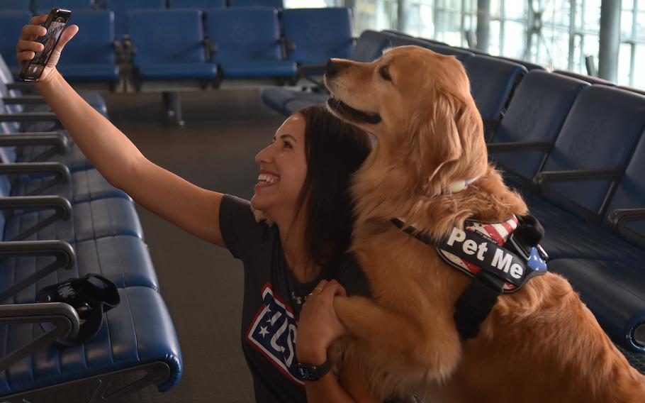 Ellie, a 7-year-old golden retriever and therapy dog, knows how to hug, a trick she practiced while getting a selfie with Beatriz Fracalosi, a USO center operations specialist and Air Force spouse on Oct. 18, 2023, at Ramstein Air Base, Germany.