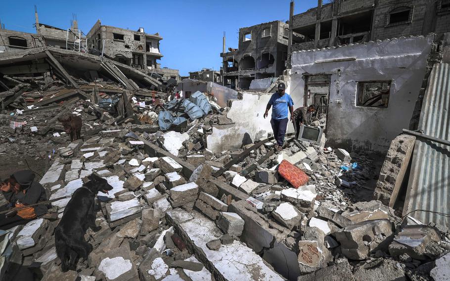 A Palestinian man and his family dog walk above the rubble of a destroyed house in the Rafah refugee camp in the southern Gaza Strip, on Thursday, March 21, 2024, amid ongoing battles between Israel and the militant group Hamas.