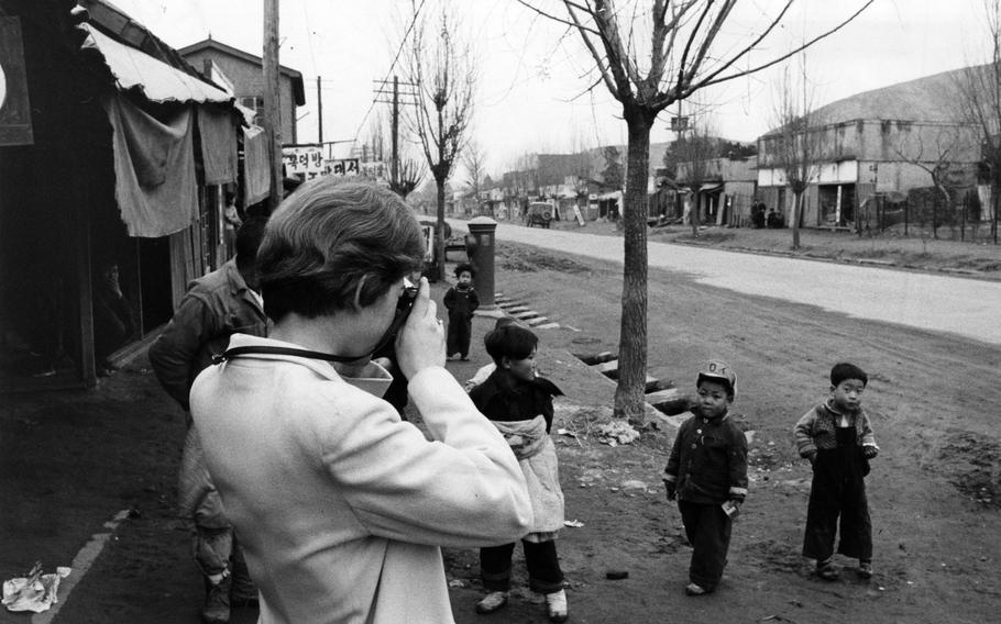 A woman takes pictures of two children