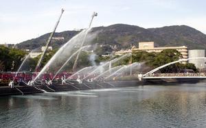 Water ejects from hoses over a body of water.