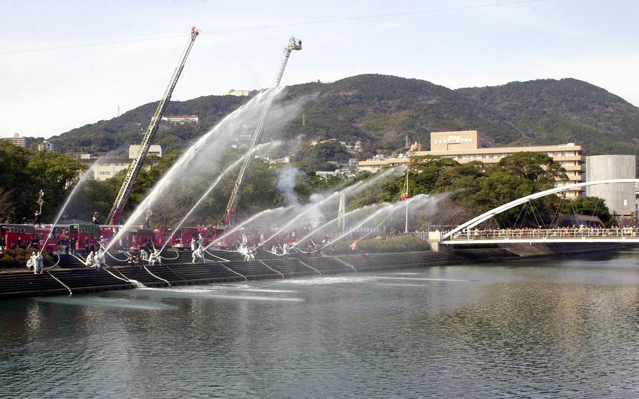 Water ejects from hoses over a body of water.