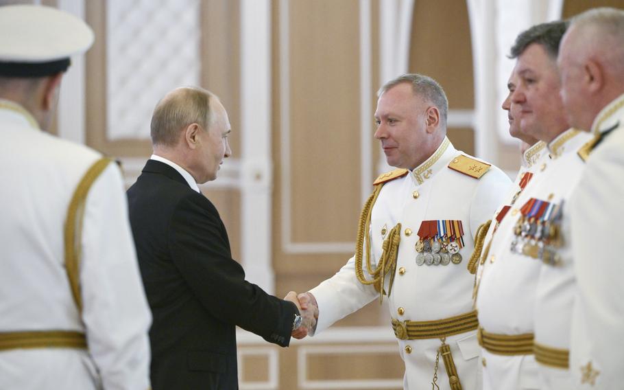 Putin shakes hands with officers.