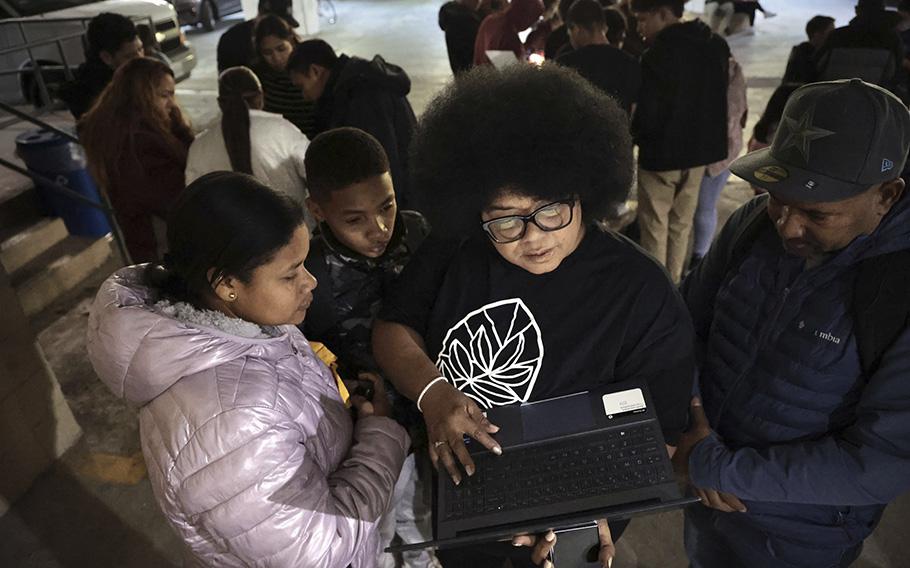 Luisette Kraal, coordinator for Nuevos Vecinos, helps Vanessa Moya Maquilon, left, and Franky Balolles Parras, both Columbian migrants, as they wait to obtain city identifications at Park Community Church in Chicago. 