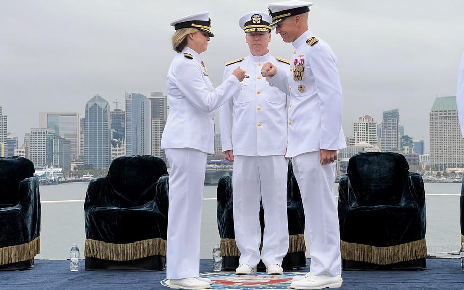 Capt. Amy N. Bauernschmidt, left, outgoing commanding officer of the Nimitz-class aircraft carrier USS Abraham Lincoln (CVN 72), shares a fist bump with her relief, Capt. Peter J. Riebe, right, during a change of command ceremony held Thursday, May 18, 2023, and presided over by Rear Adm. Kevin Lenox, commander, Carrier Strike Group 3, on the flight deck