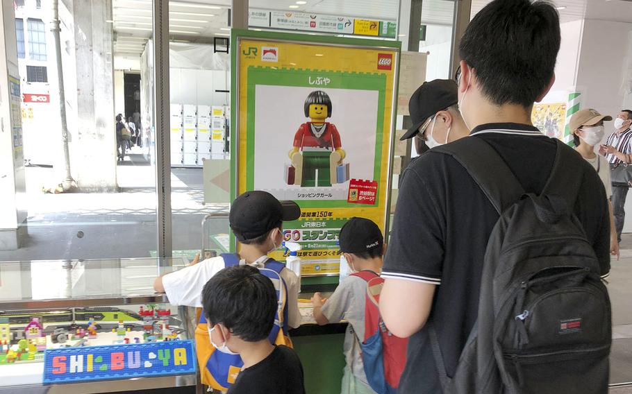 People line up to collect a special Lego stamp at Shibuya Station in central Tokyo. Shibuya's minifigure for the stamp rally is called "Shopping Girl."