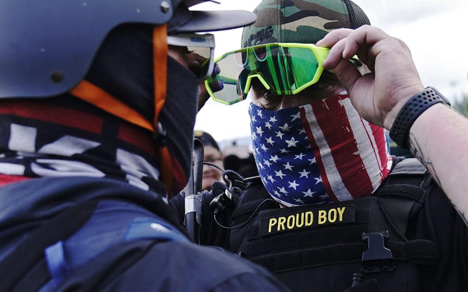 In this Sept. 26, 2020, file photo, a member of the Proud Boys, right, stands in front of a counter protester as members of the Proud Boys and other right-wing demonstrators rally in Portland.