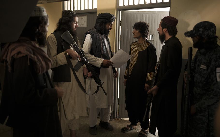 Taliban fighters talk to a detainee before transferring him to a court in Kabul, Afghanistan, Sunday, Sept. 19, 2021.