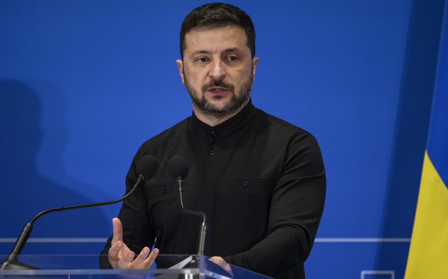 Ukrainian President Volodymyr Zelenskyy gesturing with one hand while speaking at a podium.