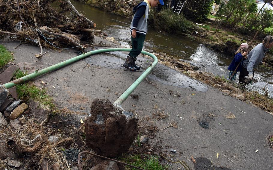 A boy steps over a metal pole uprooted during the severe floods in mid-July along the Nims River in Rittersdorf, Germany, on July 31, 2021.