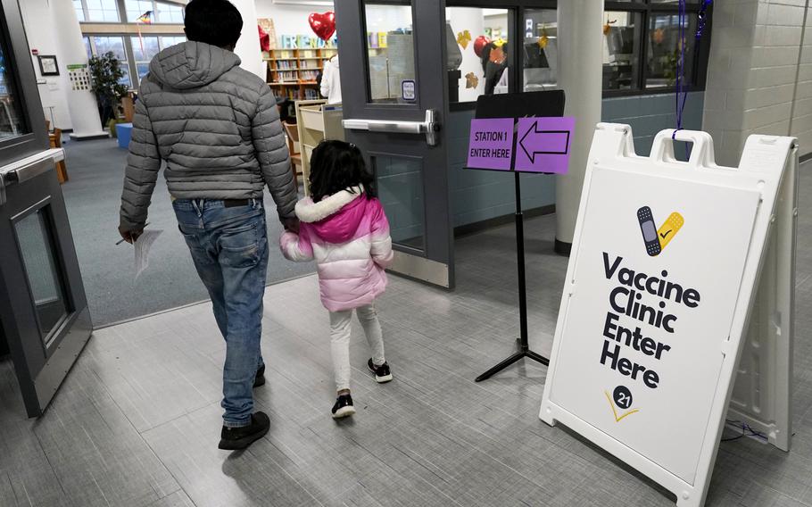 An information sign is displayed as a child arrives with her parent to receive the Pfizer COVID-19 vaccine for children 5 to 11-years-old at London Middle School in Wheeling, Ill., Wednesday, Nov. 17, 2021. (AP Photo/Nam Y. Huh)