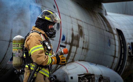 An 86th Civil Engineer Group airman stands ready with a firehose at the scene of a simulated aircraft crash at Ramstein Air Base, Germany, July 26, 2022. First responders at Ramstein practiced the crash scenario during Operation Varsity, a recurring emergency response exercise.