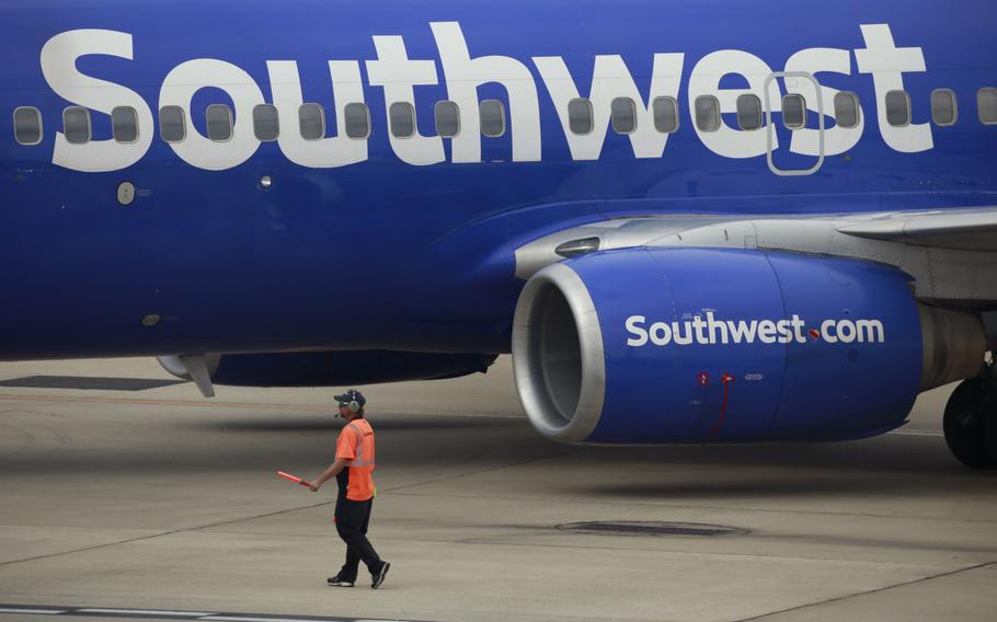 A worker directs a Southwest Airlines Boeing 737 passenger jet pushing back from a gate at Midway International Airport in Chicago on Oct. 11, 2021. 